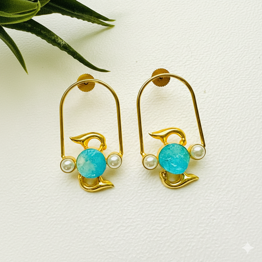 Gold dolphin earrings with turquoise stones and pearls on a white background