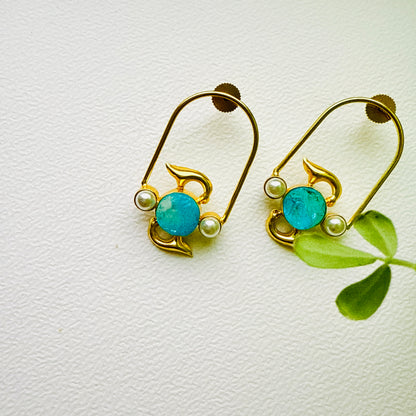 Gold earrings with turquoise stones and pearls on a white background