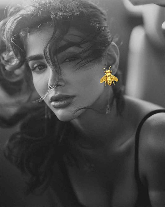 Black and white photo of a woman with a bee earring, with a blurred background