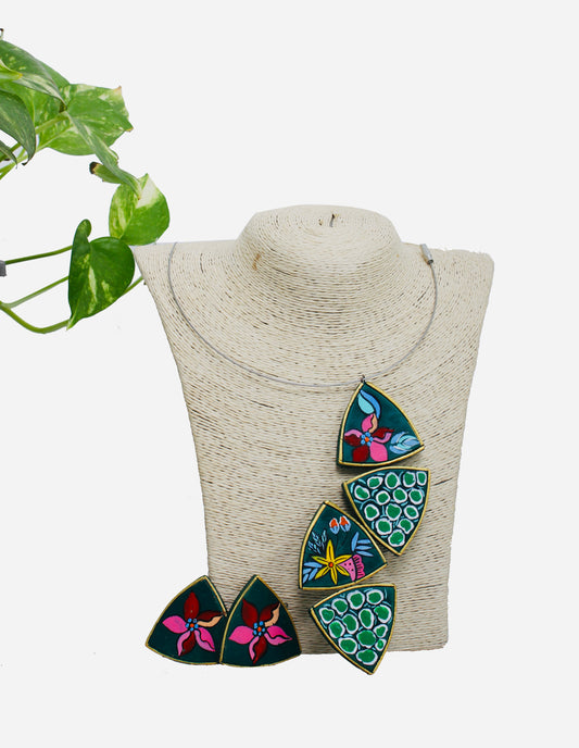 Colorful leaf-shaped earrings on a mannequin bust with a green plant in the background