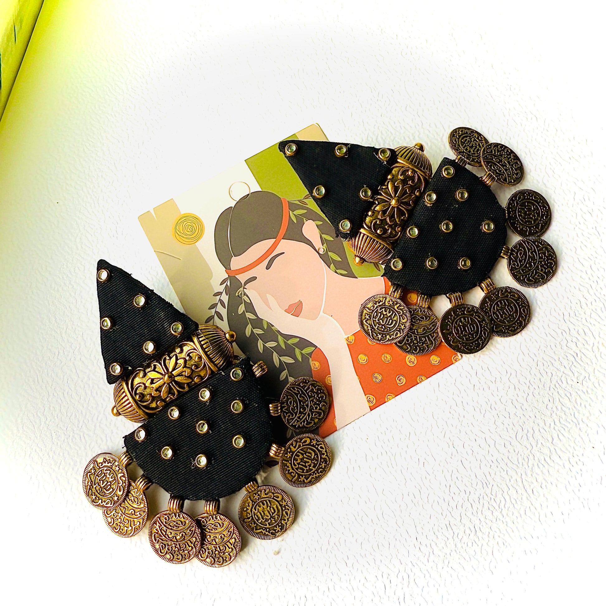 Decorative hair clip with black and gold details on a white background