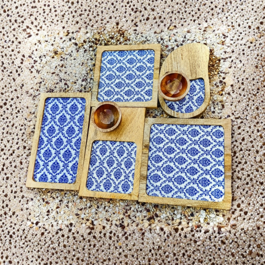 Set of wooden coasters with blue patterned designs on a textured surface