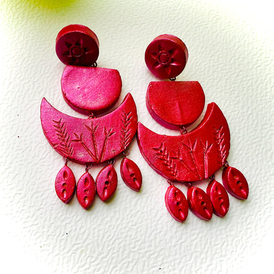 Red earrings with intricate designs on a white background