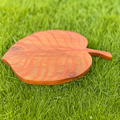 Wooden leaf-shaped cutting board on grass
