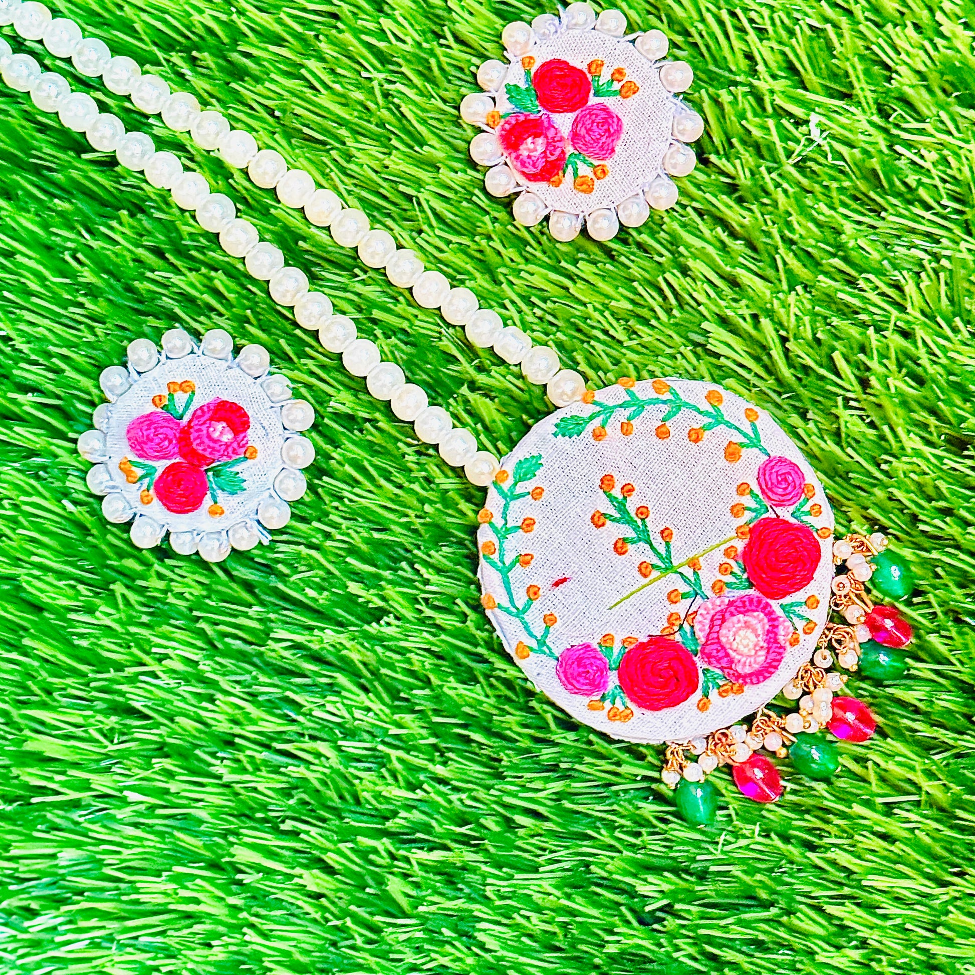Embroidered necklace with floral designs on a green grass background
