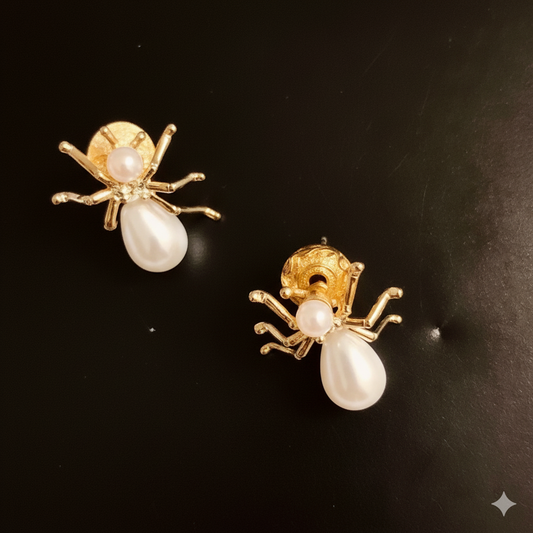 Gold ant-shaped earrings with pearl bodies on a black background