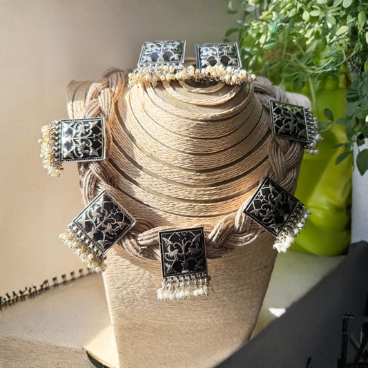 Decorative headband with black square ornaments and white tassels on a textured stand.