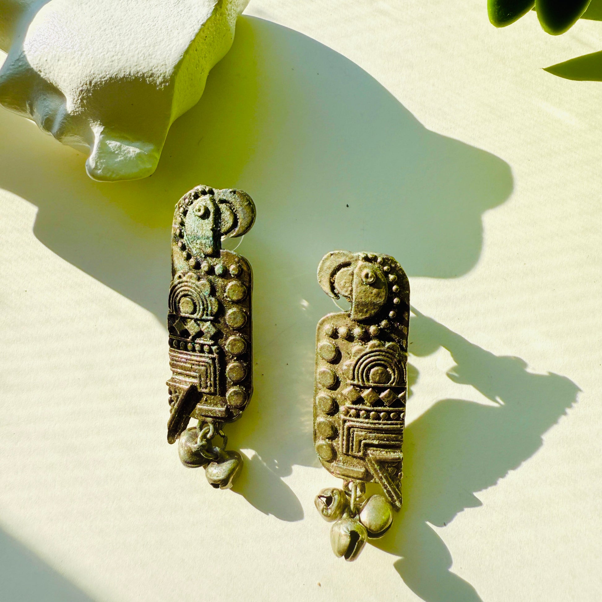 Pair of decorative earrings with intricate designs on a light background