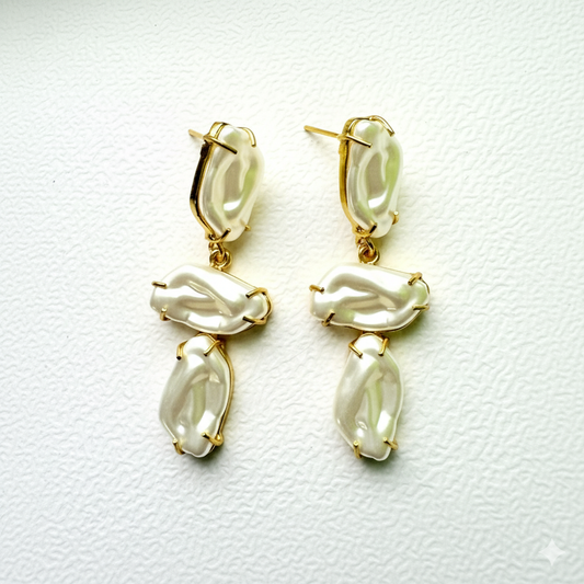 Pair of gold and pearl drop earrings on a white background