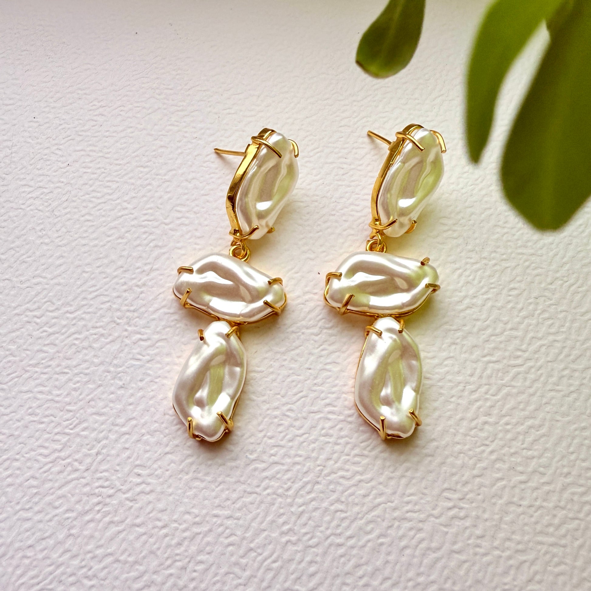 Pair of gold and pearl earrings on a light background