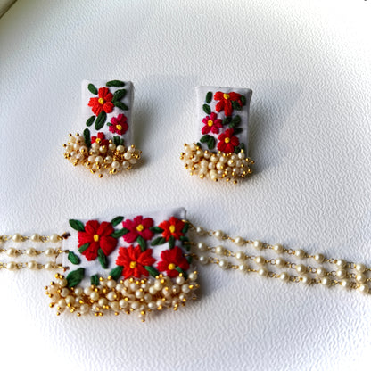 Pair of earrings with floral design and gold chain on a white background