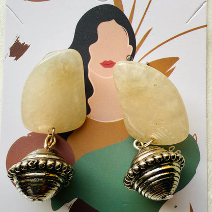 Shell-shaped earrings on a decorative card with a woman's face.