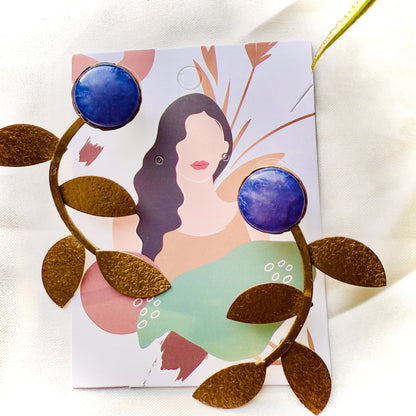 Earrings with blue and gold design on a card with an illustration of a woman.