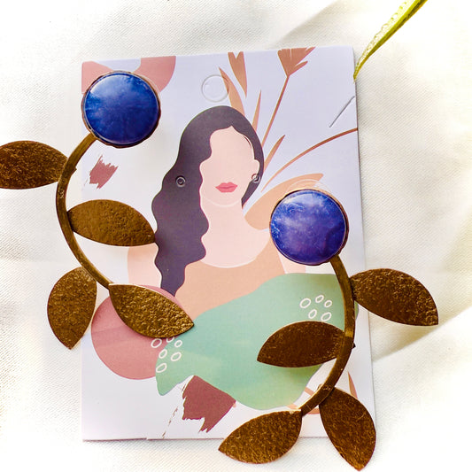 Earrings with blue and gold design on a card with an illustration of a woman.