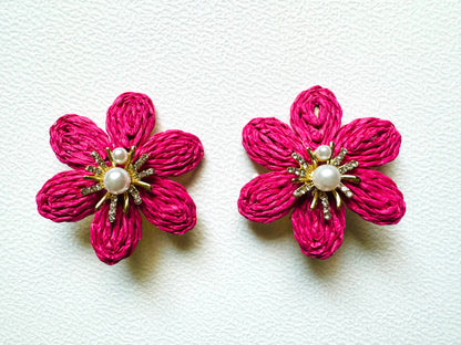 Pair of pink flower-shaped earrings with pearl centers on a white background