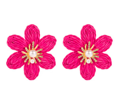 Pair of pink flower-shaped earrings with pearl and gold center on a white background