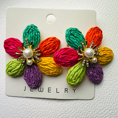 Colorful flower-shaped earrings on a jewelry card against a white background