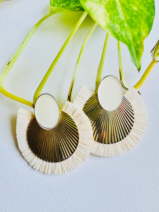 Pair of earrings with gold and white design on a light blue background