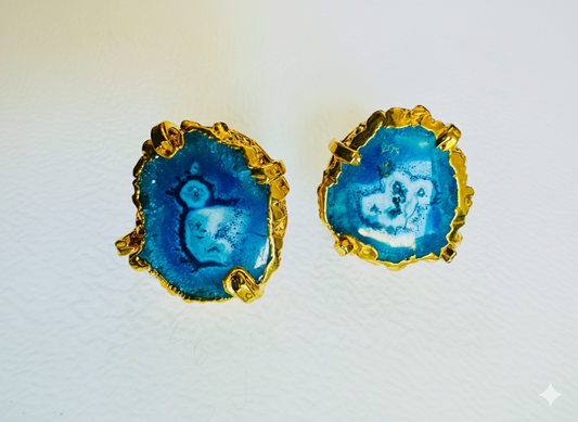 Pair of earrings with blue circular design and gold accents on a white background