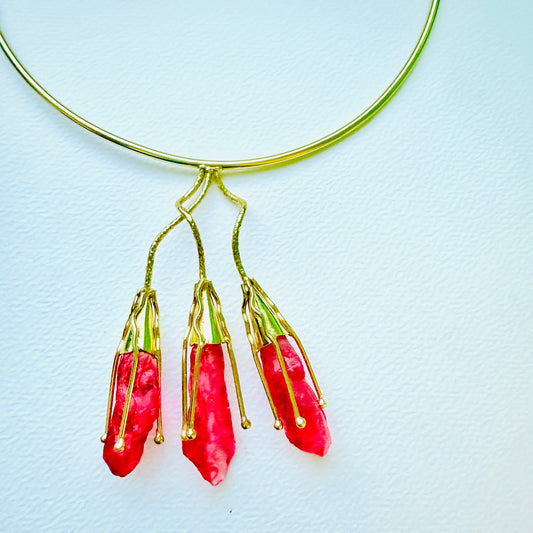 Gold necklace with red pendant on a light blue background