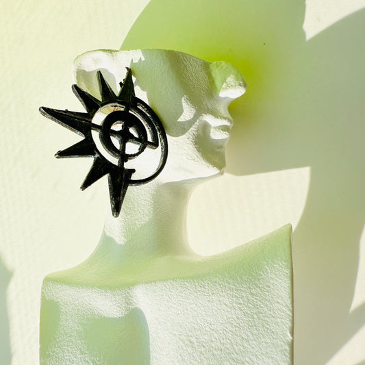 Black and silver compass-like pin on a white flower