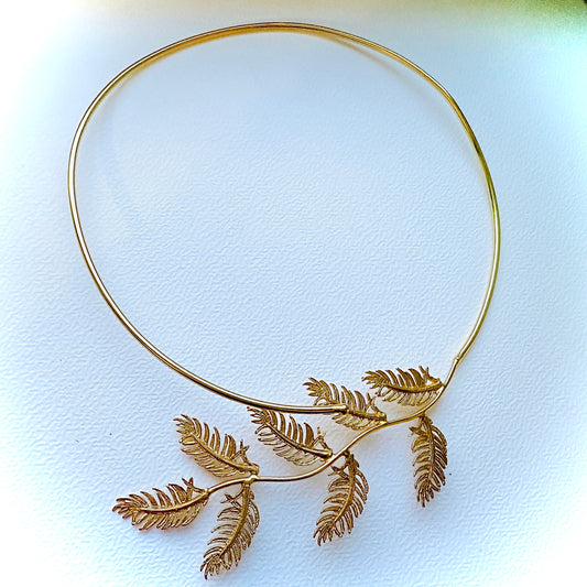 Gold leaf-shaped necklace on a white background