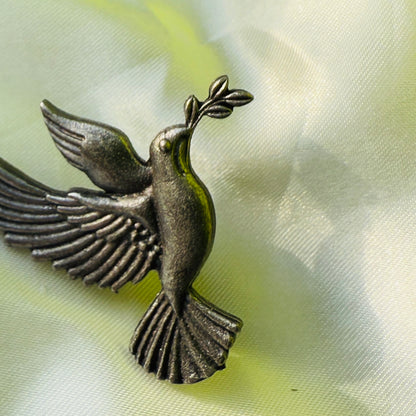 Bronze dove with olive branch on a light fabric background