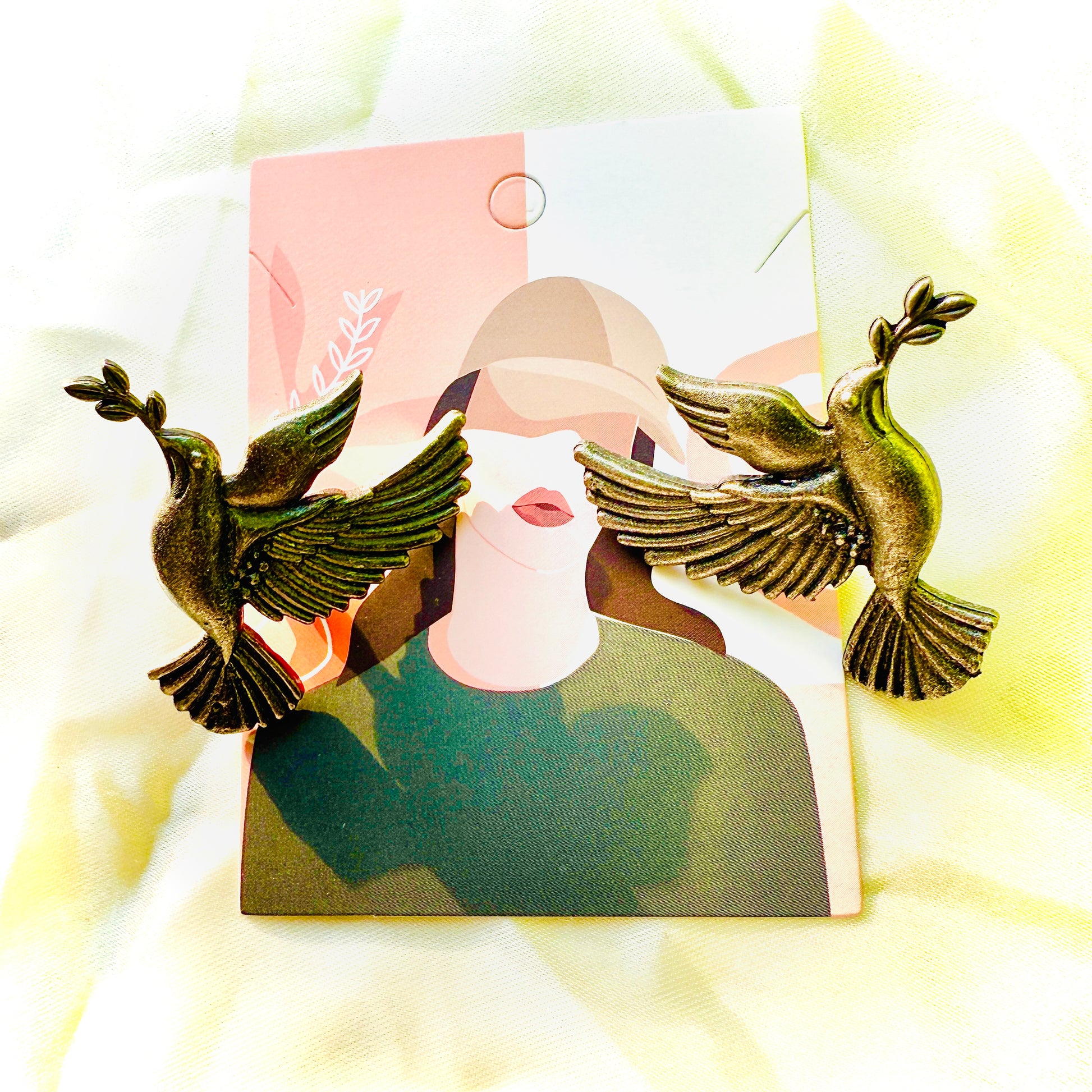 Bronze bird-shaped earrings on a blurred background