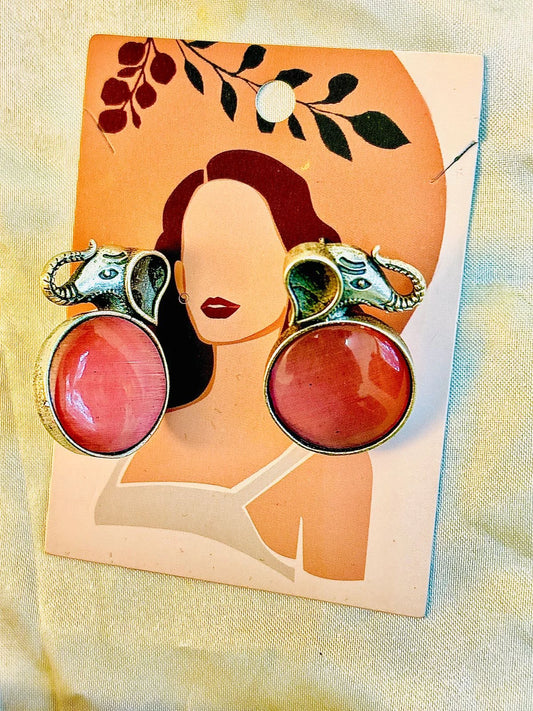 Pair of earrings with pink stones and gold accents on a card with a woman's face.