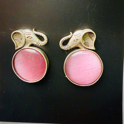 Pair of earrings with pink gemstones and gold elephant designs on a black background