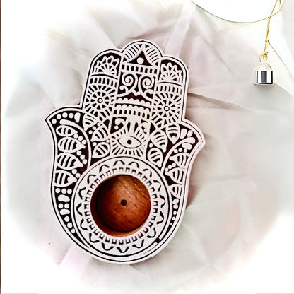 Decorative Hamsa hand with a wooden ball on a light fabric background