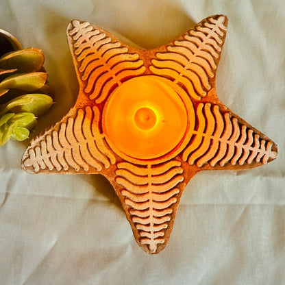 Star-shaped candle holder with a lit candle on a light fabric background