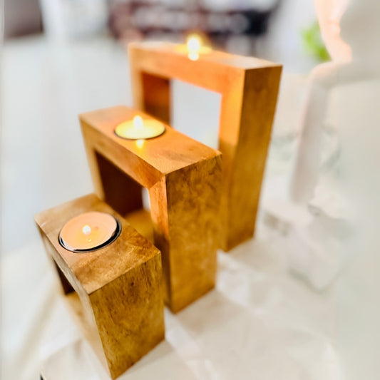 Three wooden candle holders with candles on a white surface